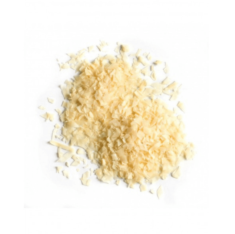 Close-up of light yellow Soap Flakes (per 100g) scattered on a white background in small piles