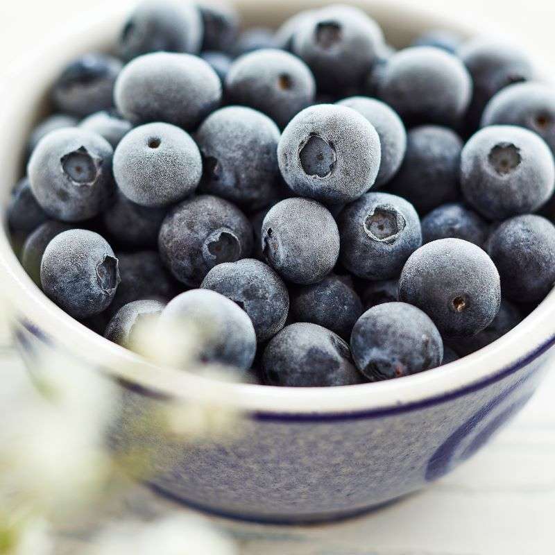 Close-up of a bowl filled with frozen blueberries.