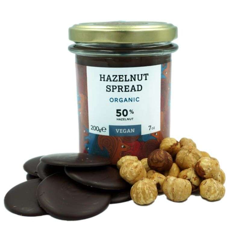 Jar of hazelnut spread with hazelnuts and chocolate cookies on a white background
