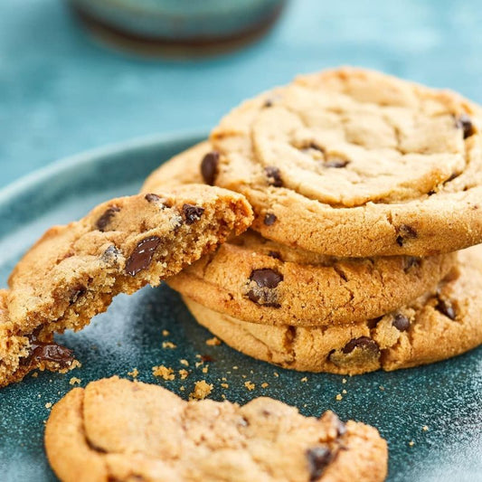 Stack of chocolate chip cookies on a blue plate with one cookie broken in half.