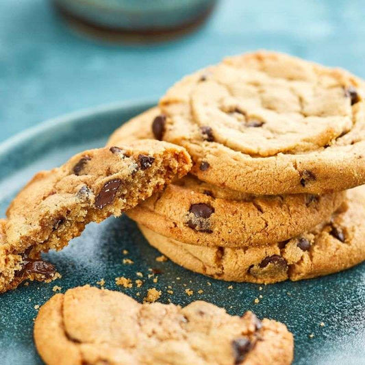 Stack of chocolate chip cookies on a blue plate with one cookie broken in half.