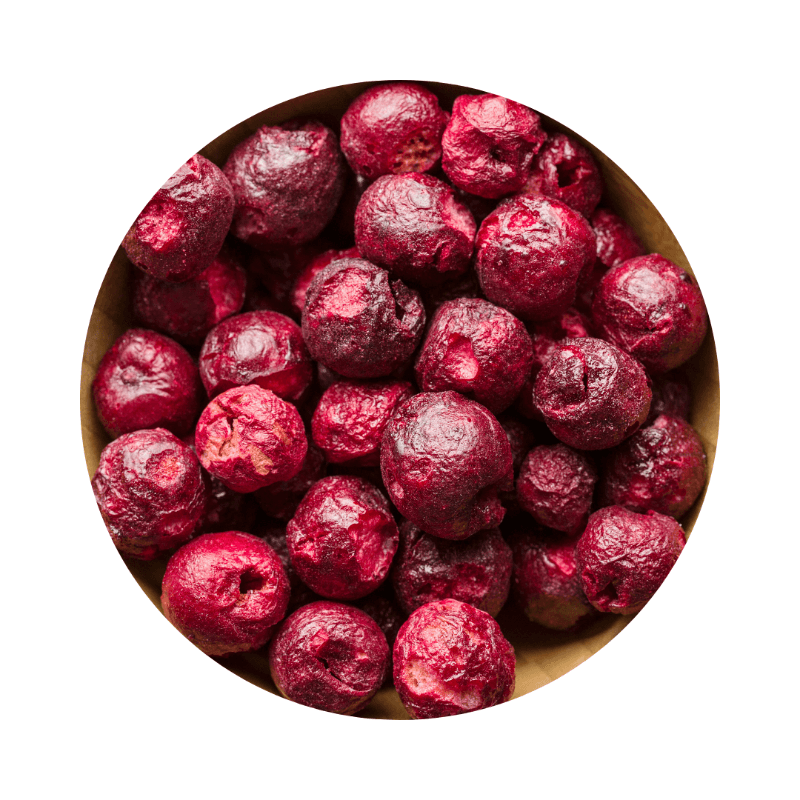 Close-up of vibrant red freeze-dried sour cherries sliced (per 100g) in a wooden bowl, showing detailed texture.
