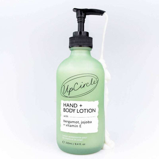 Green bottle of UpCircle hand and body lotion on a white background