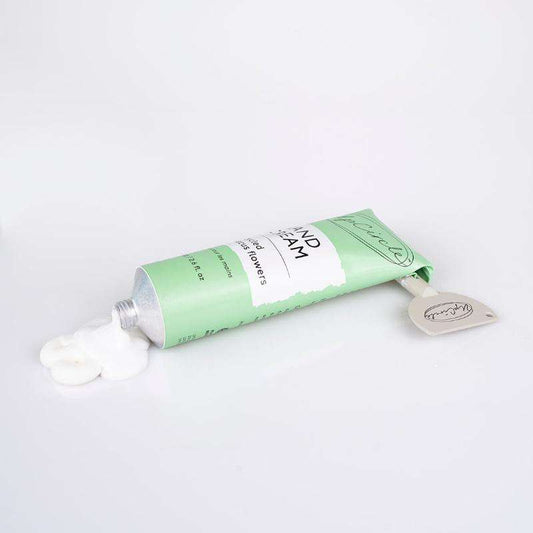 Green tube of hand cream with a white cap on a light gray background