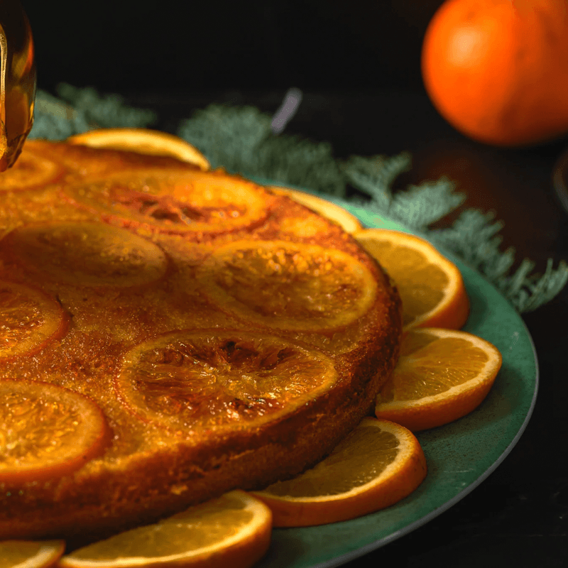 Candied Orange Slices (per 500g) displayed on a plate with fresh orange slices in a warm, inviting setting