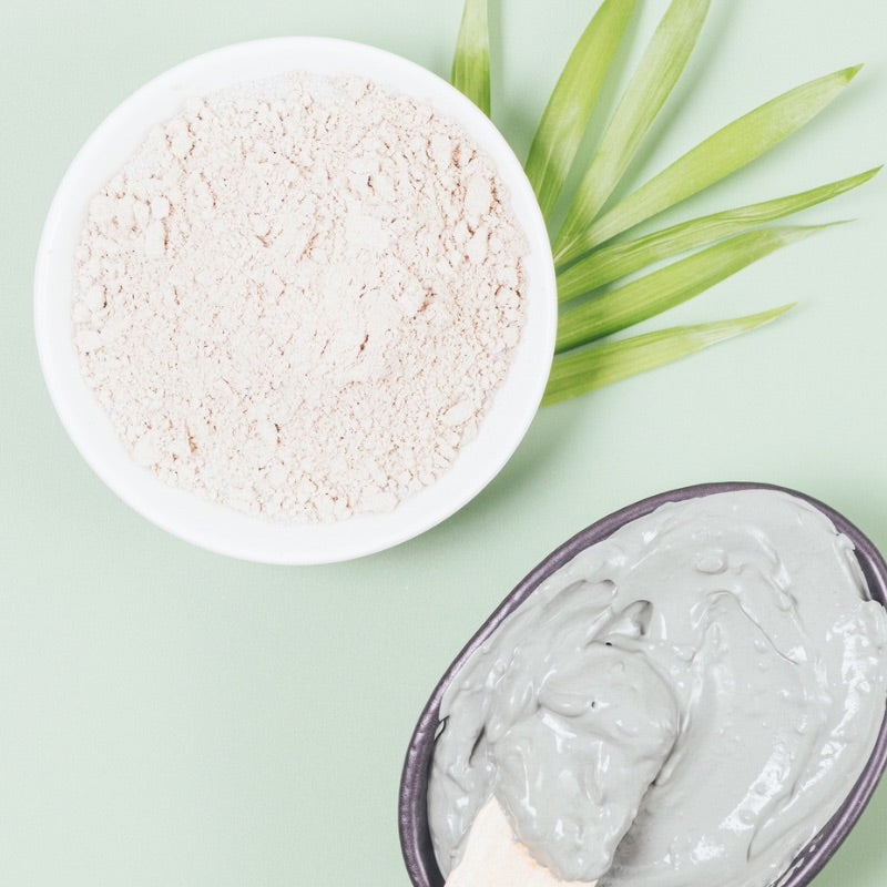 Kaolin Clay Powder (30g) natural clay powder in bowl with applied clay mask on spatula, green leaves background