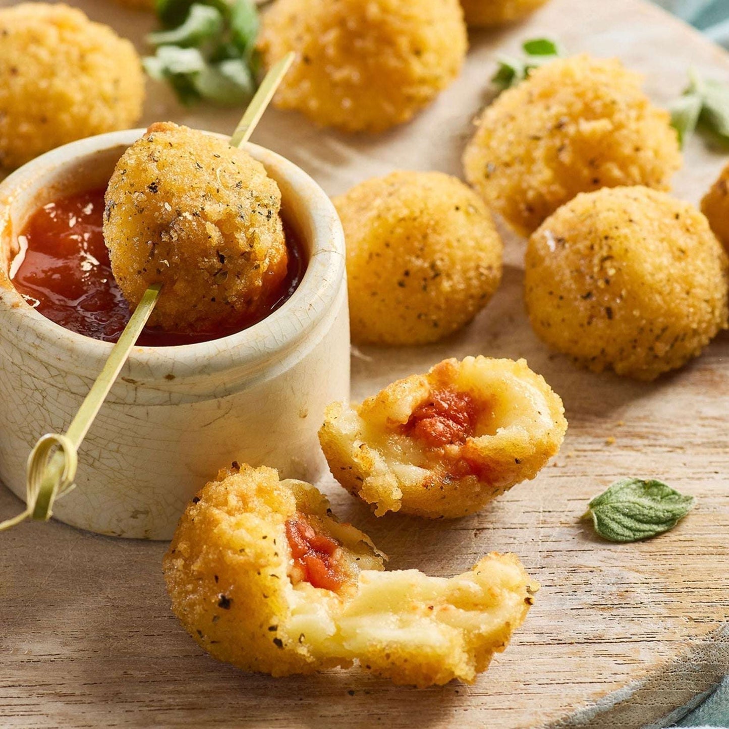 Small fried appetizers with tomato sauce on a wooden board