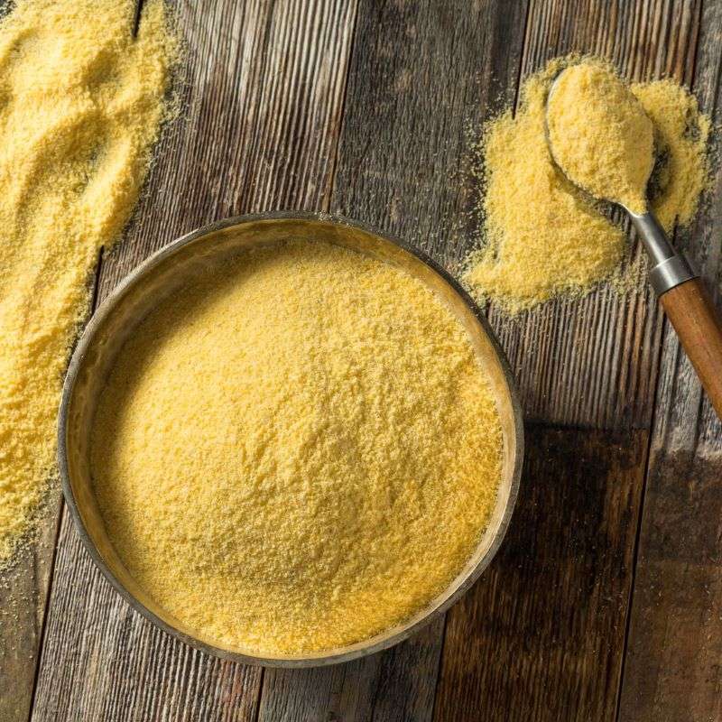 Polenta ORGANIC (per 500g) in a bowl with a wooden spoon on a rustic wooden surface, natural and sustainable.
