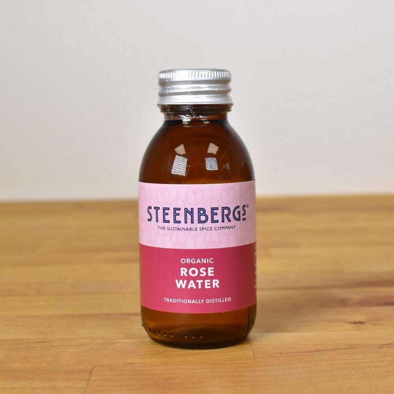 Small amber bottle of Rose Water ORGANIC (100ml) with sustainable and cruelty-free packaging on wooden surface