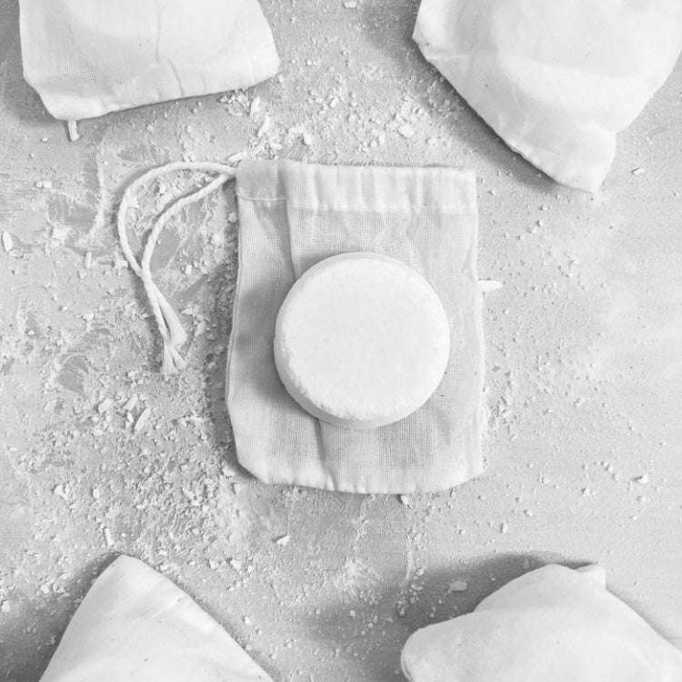 Round white shower steamer on a textured surface with fabric bags.
