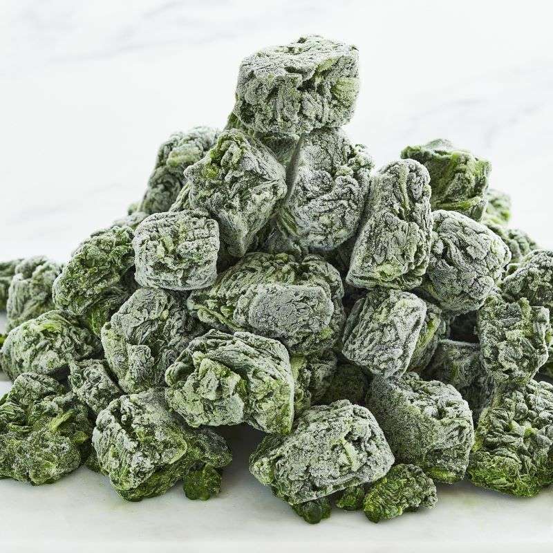 Green frozen frozen spinach leaves stacked on a white background
