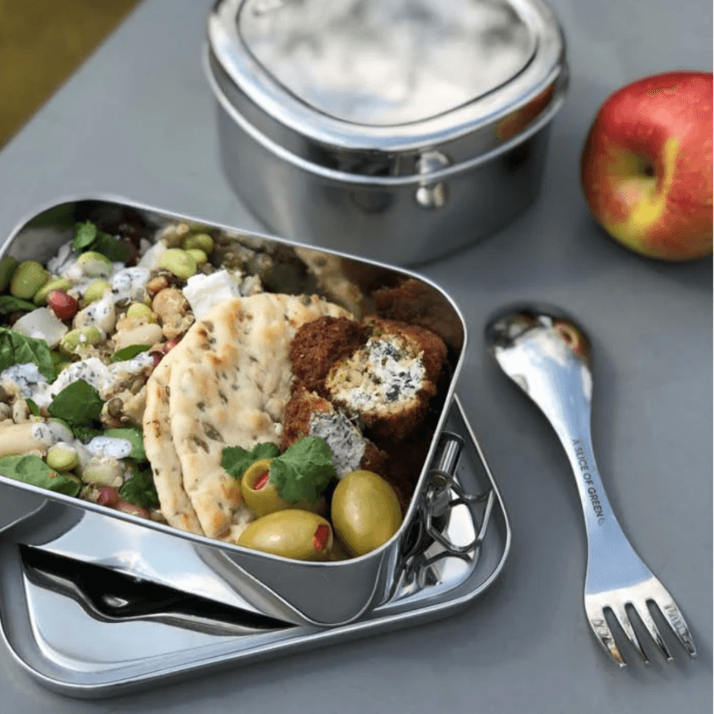 Lunchbox with food, apples, and utensils on a table