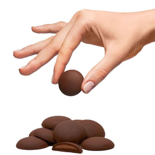Hand holding one Dark & Salted ALMOND Giant Chocolate Buttons ORGANIC (per 100g) above pile of smooth chocolate buttons