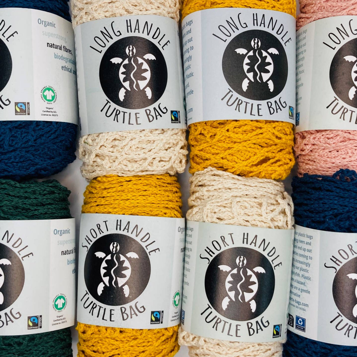 Six skeins of yarn arranged in two columns, each wrapped with a white label reading 'LONG HANDLE TURTLE BAG' and 'SHORT HANDLE TURTLE BAG.' The yarn colors visible are dark blue, cream, mustard yellow, peach pink, and dark green.