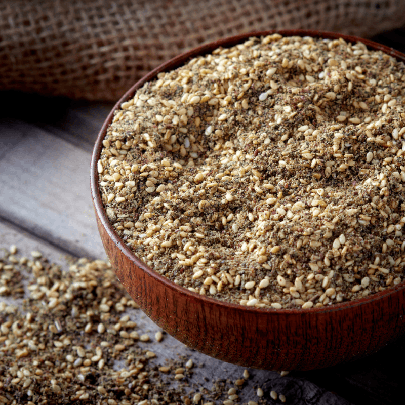 Close-up of Za'atar (per 100g) spice blend in a wooden bowl on a rustic surface, natural and sustainable refill product