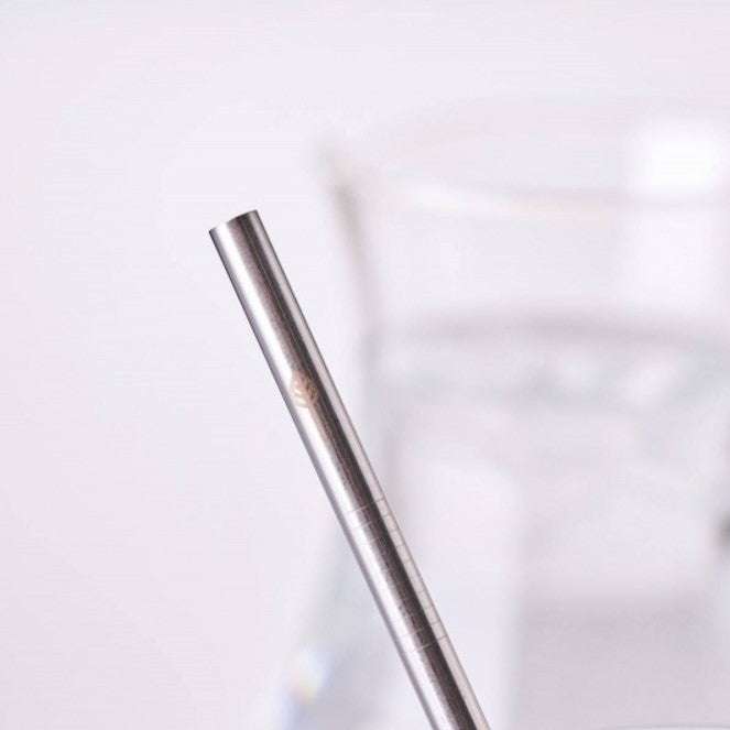 Close-up of a Stainless Steel Drinking Straws (singles) with a blurred glass of water in the background.