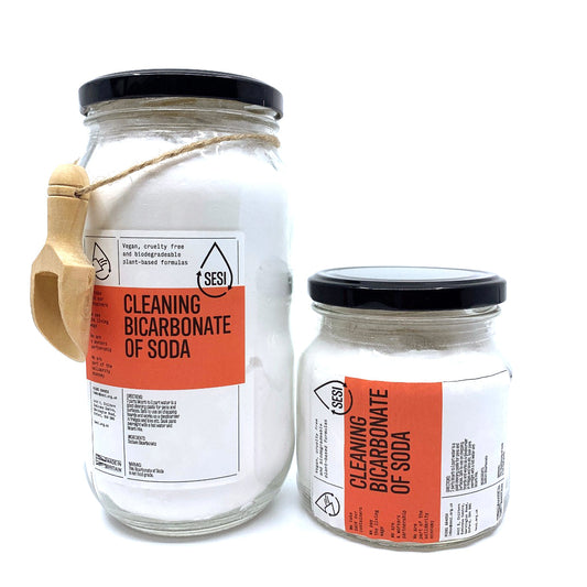 Two glass jars filled with CLEANING Bicarbonate of Soda featuring eco-friendly packaging and a wooden scoop attached to one jar