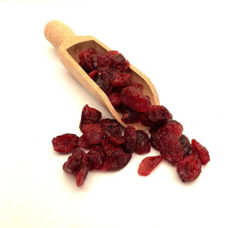 Cranberries ORGANIC (per 200g) dried vibrant red cranberries spilling from a small wooden scoop on white background
