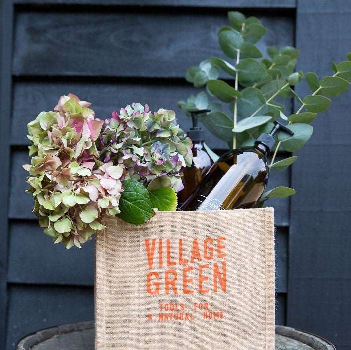 Jute bottle bag holding amber glass bottles and fresh flowers for an organic, plastic free refill shop display
