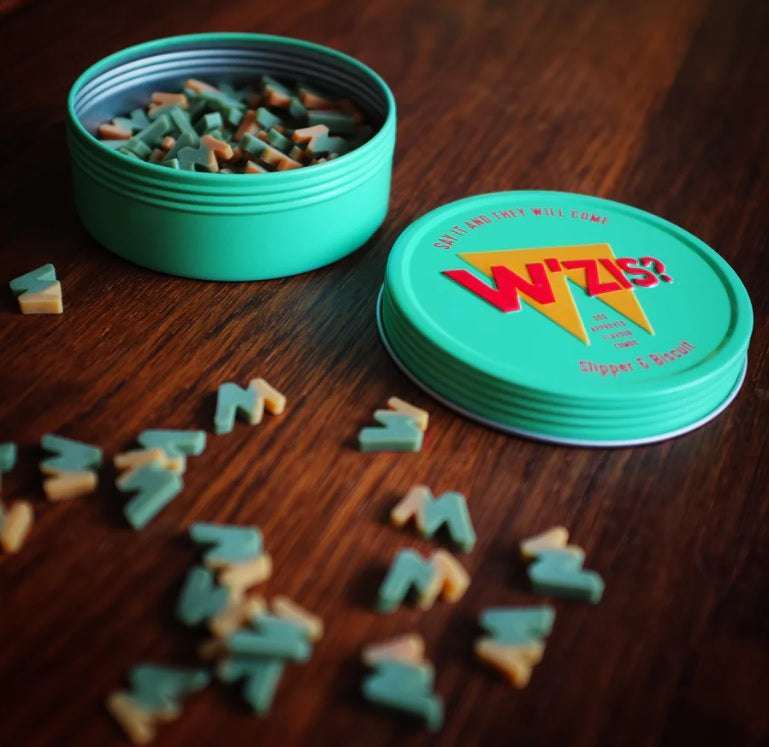 Green container with dog treats on a wooden surface, featuring the brand 'Wiz'.