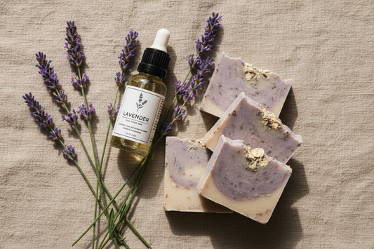 Lavender sprigs laid with a bottle of lavender essential oil and bars of lavender soap