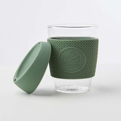 Clear glass mug with green silicone sleeve and lid on a white background