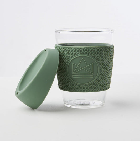 Clear glass mug with green silicone sleeve and lid on a white background