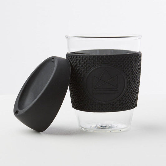 Glass cup with black textured sleeve and lid on a white background