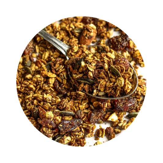 A spoonful of granola containing oats, nuts, and dried fruits, with a background of more granola.