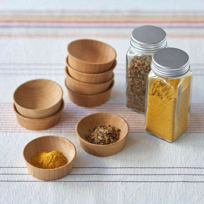 Bamboo Small Condiment Cup filled with spices next to glass spice jars on a striped cloth surface