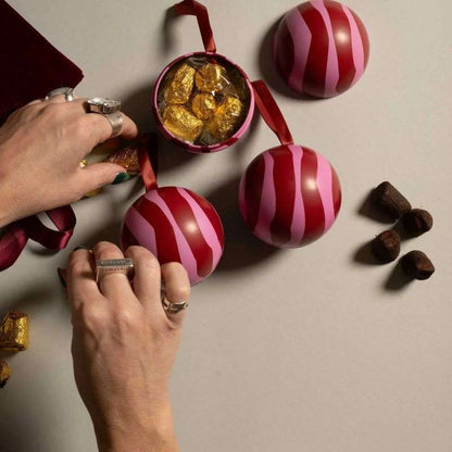 Hands arranging chocolate eggs and truffles on a neutral background