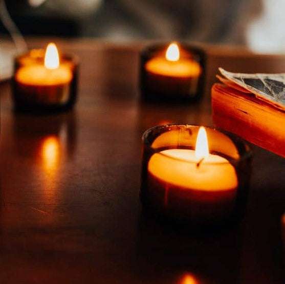 Three lit candles on a wooden surface with a blurred background