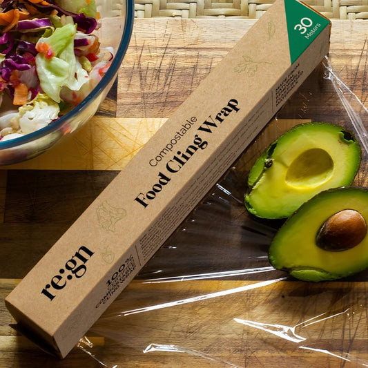 Box of re:gn compostable food cling wrap with half an avocado and salad on a wooden surface