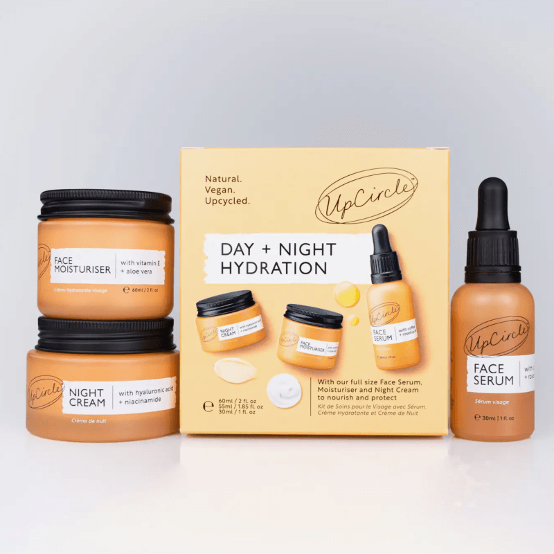 UpCircle skincare products including jars, a box, and a dropper bottle on a light gray background