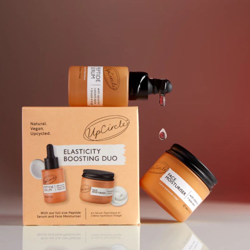 UpCircle skincare products including jars and a box on a gradient background
