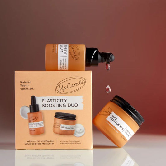 UpCircle skincare products including jars and a box on a gradient background