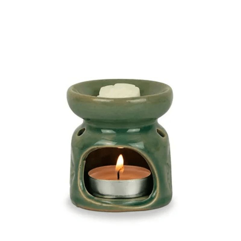 Green ceramic oil burner with a lit candle inside on a white background