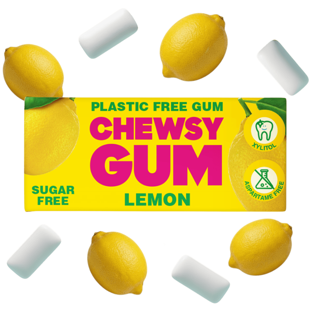 Lemon-flavored chewy gum packaging shown on a white background, surrounded by several white cylindrical gum pieces and whole lemons. The box reads 'CHEWSY GUM' with 'LEMON' below, plus 'PLASTIC FREE GUM', 'SUGAR FREE', and icons for aloe, fluoride-free, and aspartame-free.