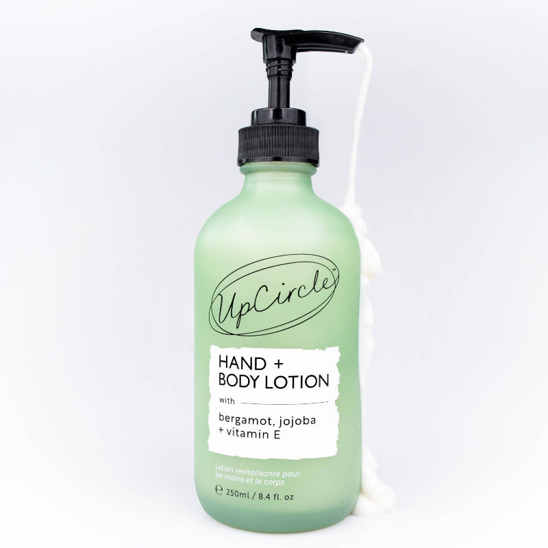Green bottle of UpCircle hand and body lotion on a white background