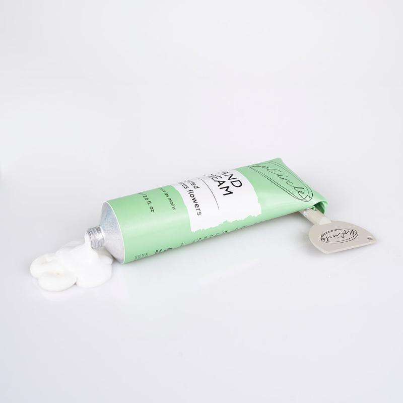 Green tube of hand cream with a white cap on a light gray background