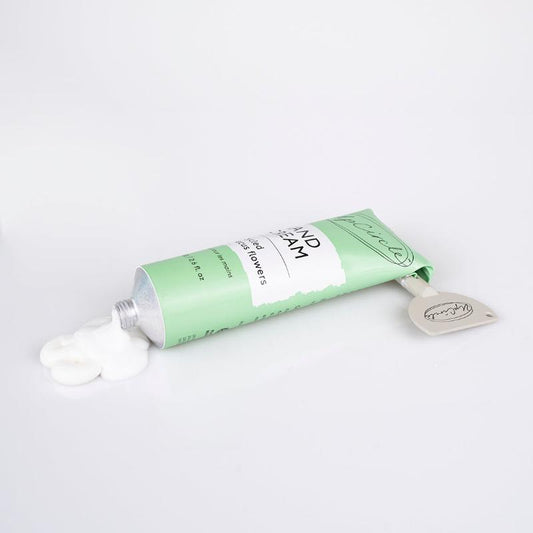 Green tube of hand cream with a white cap on a light gray background