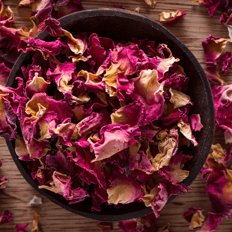 Close-up of a bowl filled with vibrant pink and yellow dried botanical flowers labeled Dried Botanical Flowers (50g)