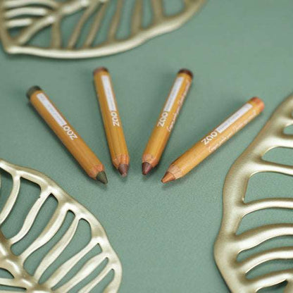 Four Jumbo Pencil ORGANIC crayons in natural wood casing on a green surface with decorative gold leaves around them