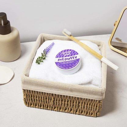 Natural ORGANIC Deodorant in Tin placed on a white towel inside a woven basket with a bamboo toothbrush and lavender sprig nearby