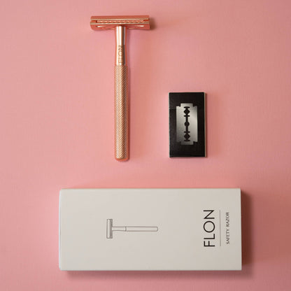 Rose gold razor, black razor blade, and white box with 'FLON' branding on a pink background