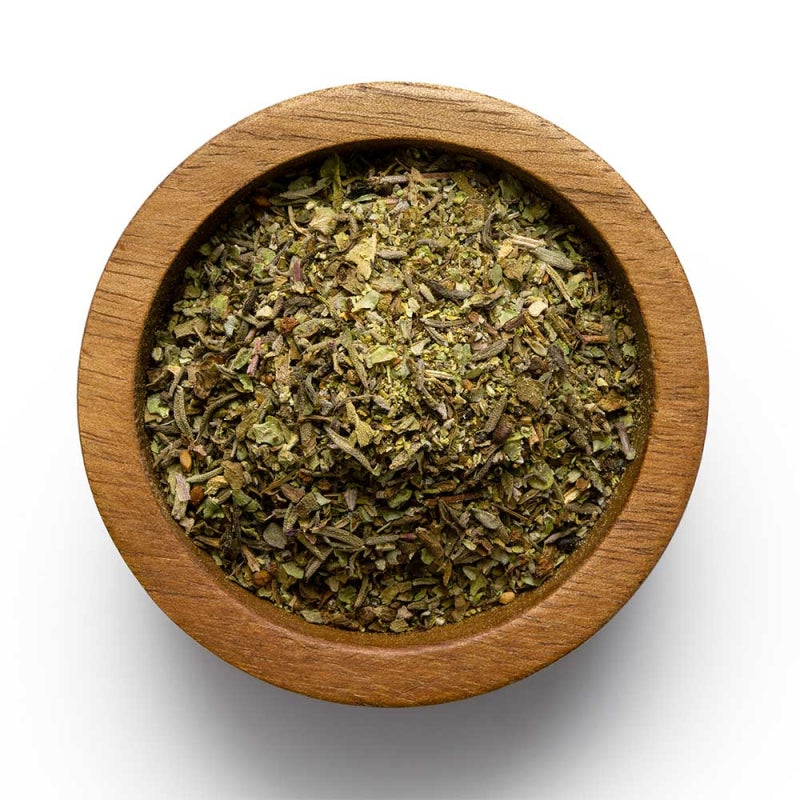 A wooden bowl filled with Italian mixed herbs, including oregano, basil, marjoram, thyme, sage, and peppercorns.