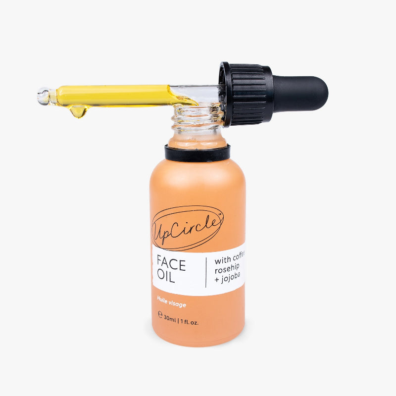 Bottle of UpCircle Face Oil with dropper on a white background
