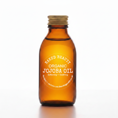 A small amber glass bottle of Naked Beauty Organic Jojoba Oil with a gold screw cap and a white circular label, centered on a clean white background.