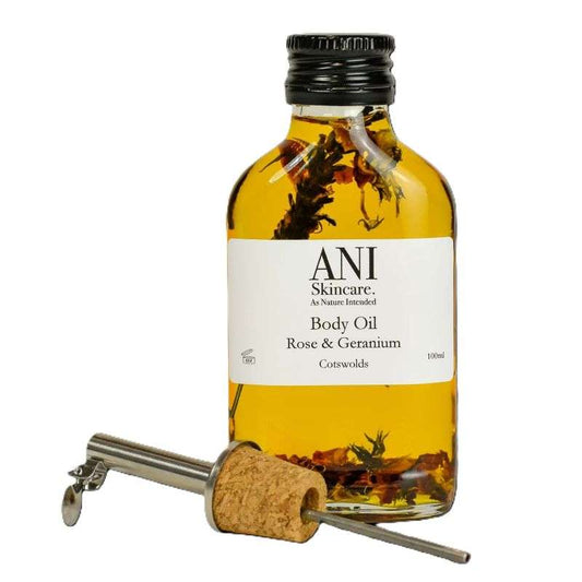 Body oil bottle with cork and metal tool on a white background, featuring ANI Skincare branding.
