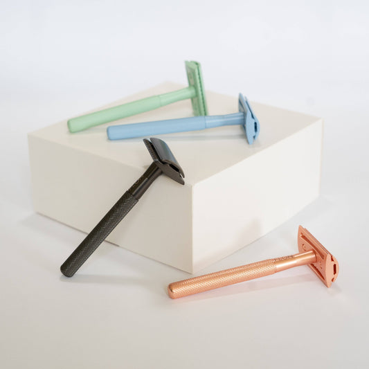 Set of four safety razors in different colors on a white background